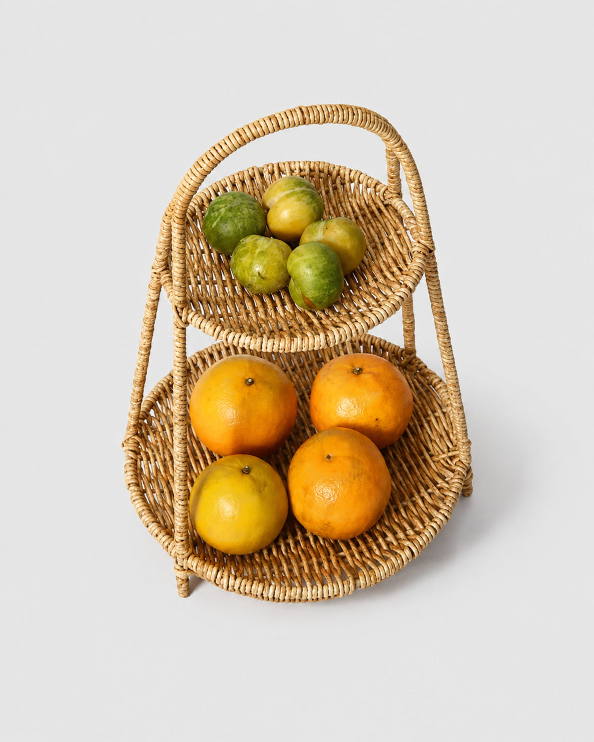 Front view of Aina two-tier faux rattan fruit tray filled with citrus and apples