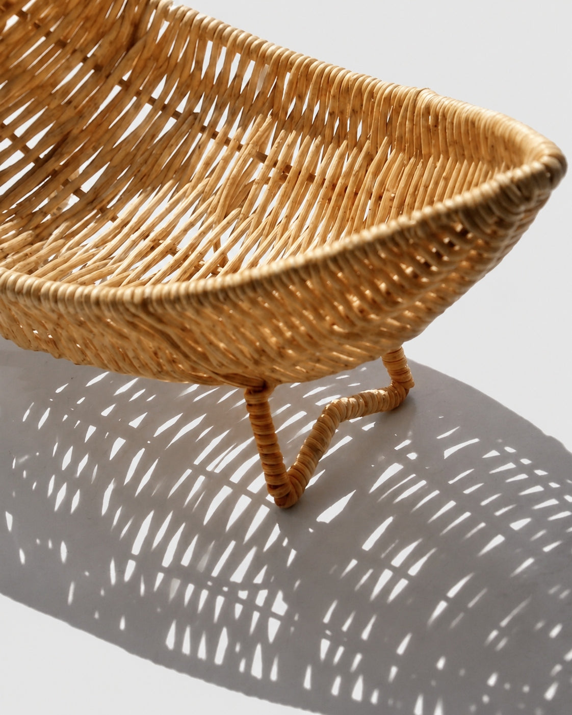 Close-up of Haldor raised fruit bowl’s open faux rattan weave and woven loop foot