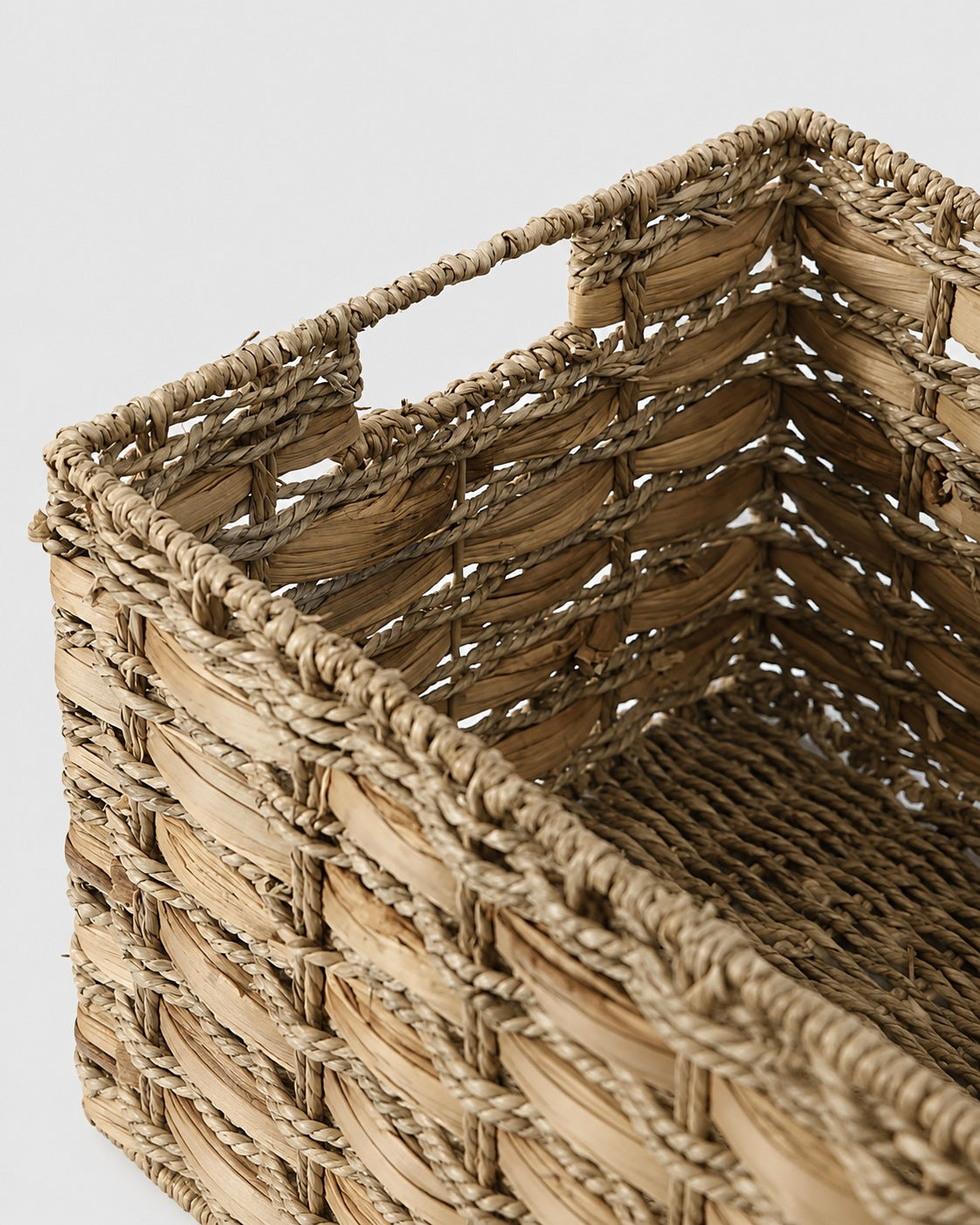 Close-up view inside the Inga grass woven storage basket showing its open weave and handle detail