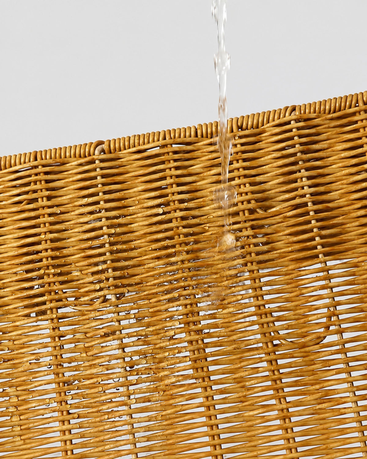 Close-up of water on Mila faux rattan woven surface, illustrating its wipe-clean finish
