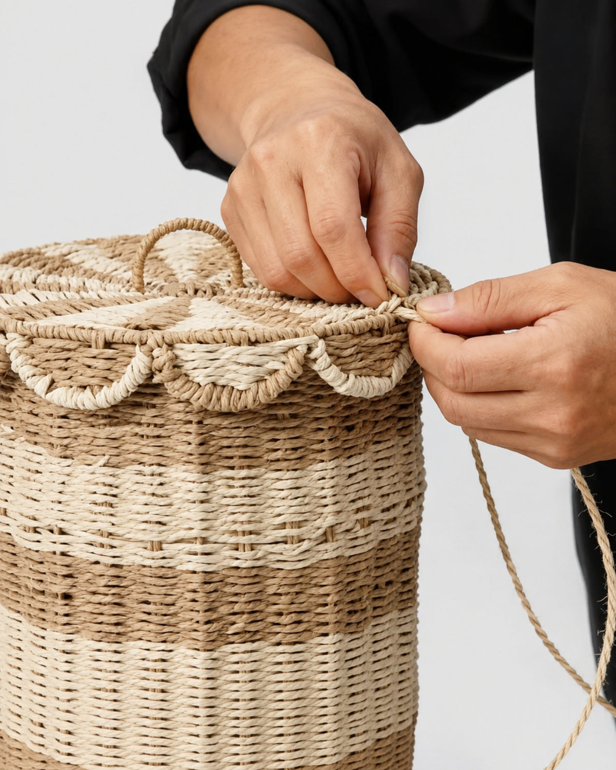 Artisan handweaving the paper rope edge and scalloped trim of Noa’s lidded laundry hamper