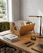 Rattan magazine organizer holding books beside a home workspace