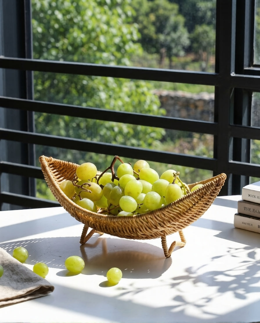 Haldor raised faux rattan fruit bowl holding grapes on a tabletop by a window