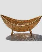 Side view of Haldor boat-shaped faux rattan fruit bowl on raised woven feet