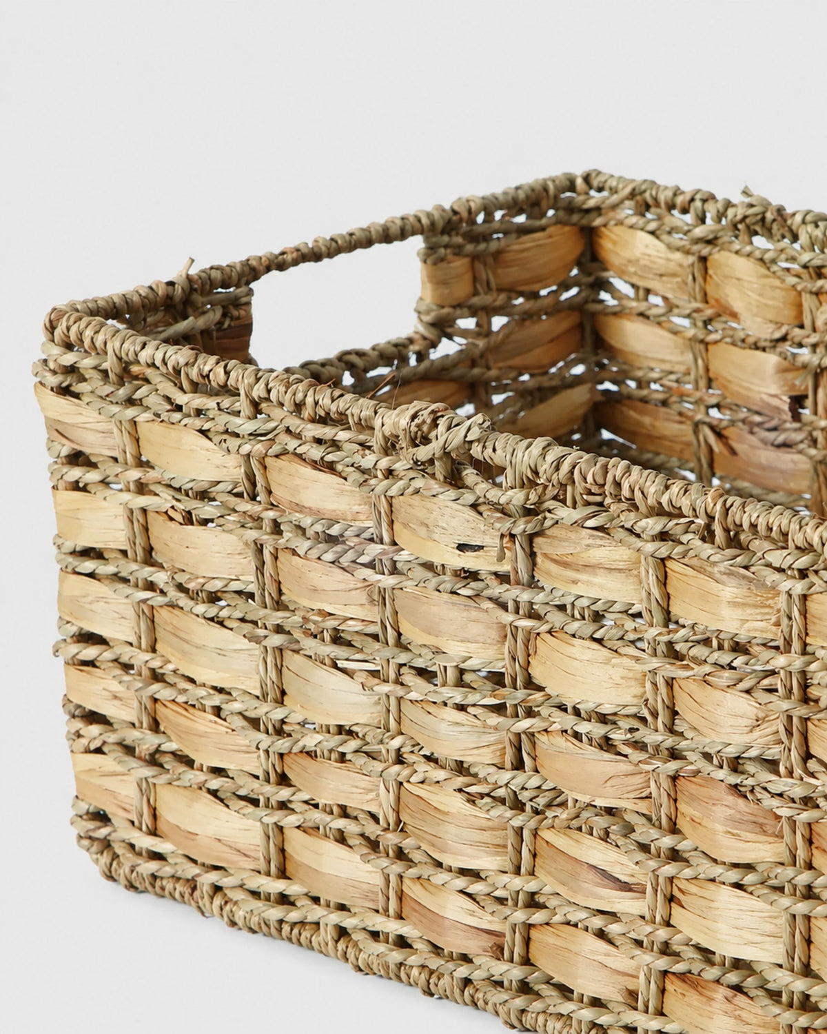 Close-up of Inga basket’s broad natural grass weave, braided edge and integrated handle opening