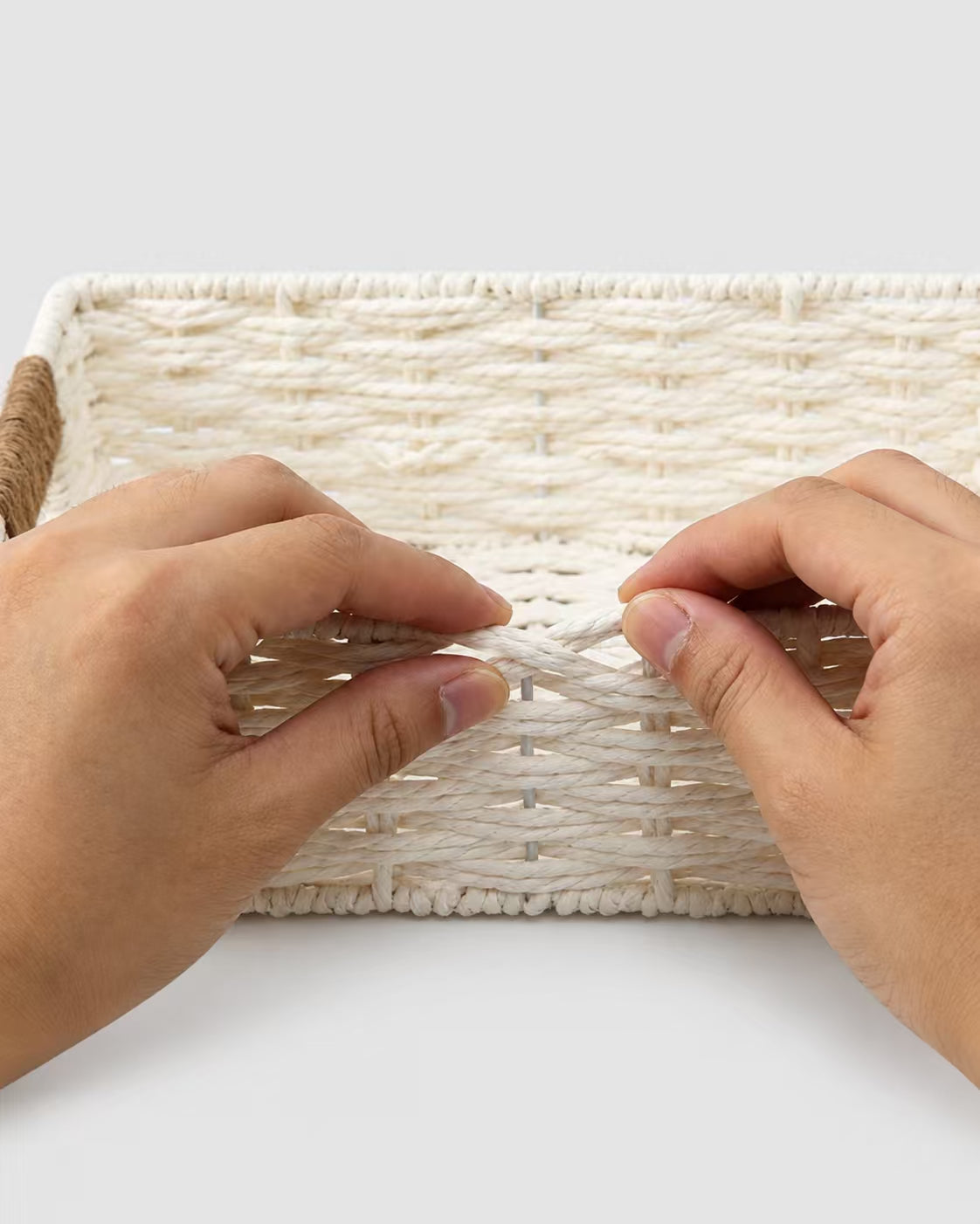 Close-up of hands holding the white paper rope weave on Kaja storage basket
