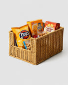 Mila natural faux rattan open-front snack basket holding packaged crisps, crackers and nuts