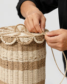 Artisan handweaving the paper rope edge and scalloped trim of Noa’s lidded laundry hamper