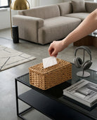 Hand pulling a tissue from Ragnhild woven paper rope tissue box cover on a living-room table